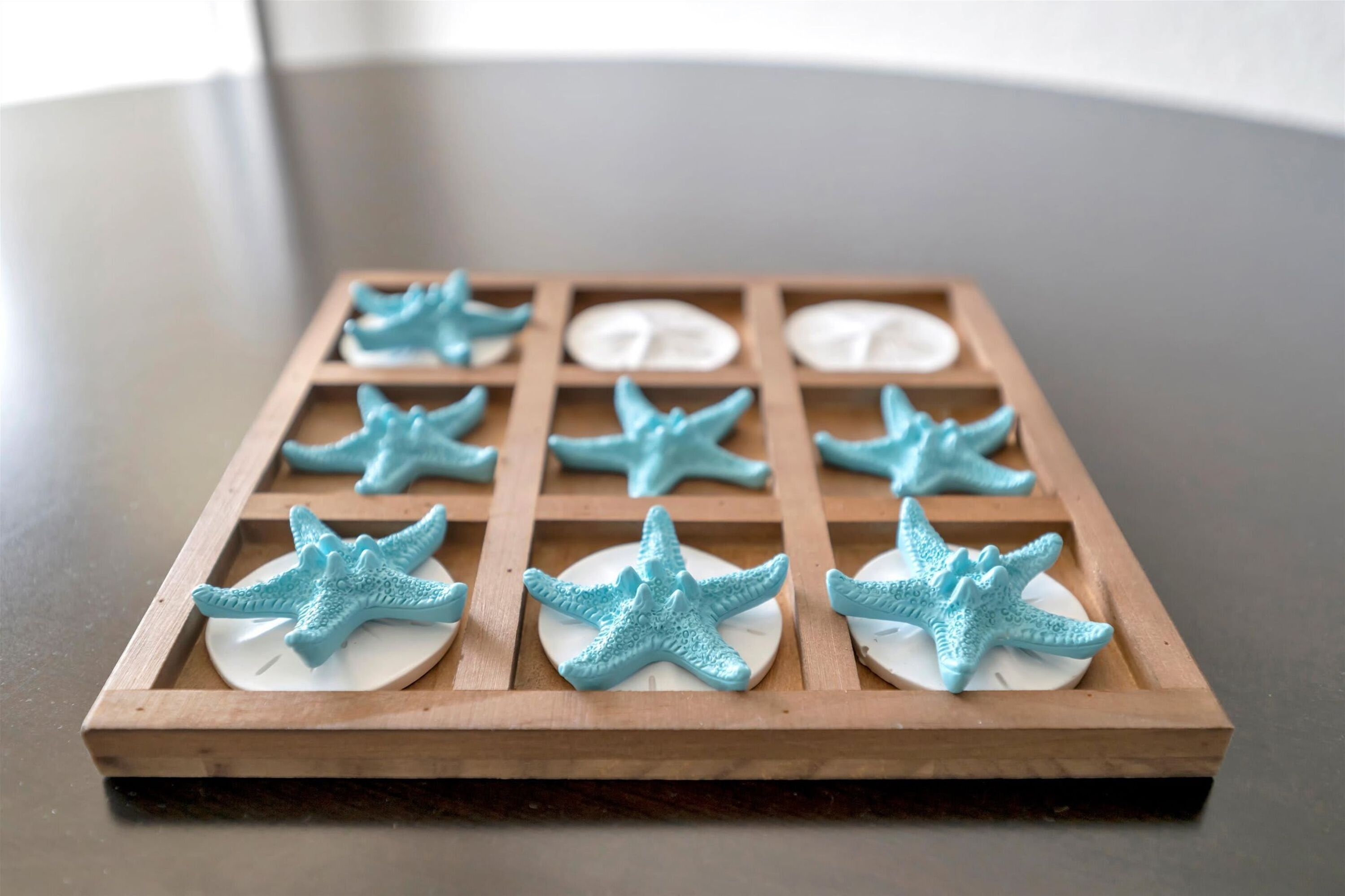 Una bandeja de madera con varios compartimentos, cada uno con una base circular blanca y una figurita de estrella de mar azul.