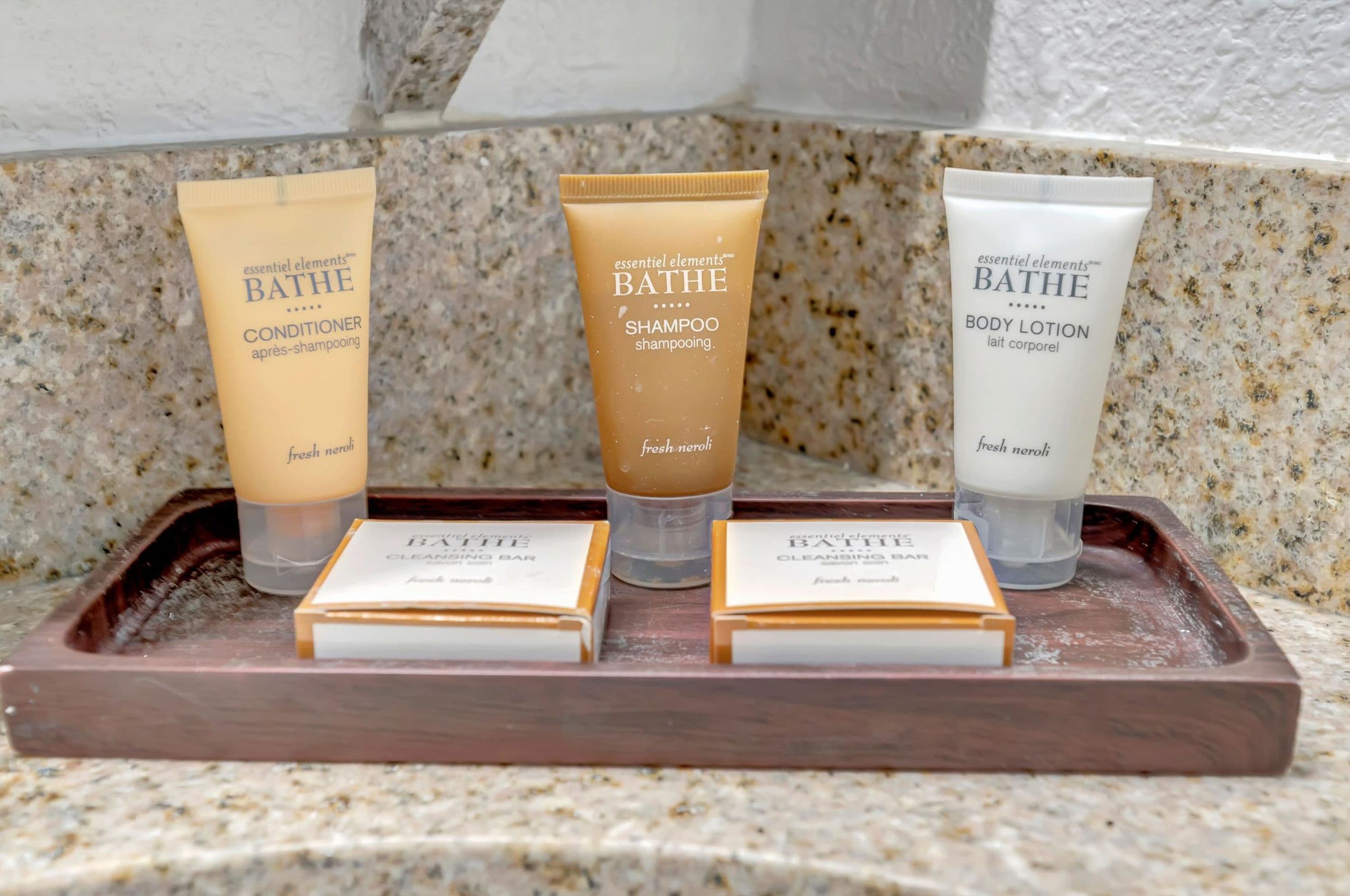 Uma bandeja com três produtos essenciais para o banho: condicionador, shampoo e loção corporal.