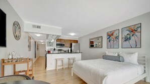Un dormitorio moderno con una cama grande, una kitchenette pequeña y un comedor.