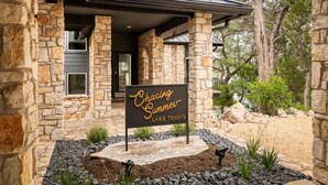 Ein Steinhaus mit einem Schild, auf dem ‚Chasing Summer Lake Travis‘ steht.