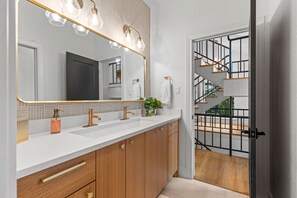 A modern bathroom with a large mirror, two sinks, and wooden cabinets. - Chasing Summer - Private Lakefront Luxury on Lake (Point Venture)