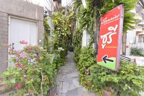 A narrow stone pathway flanked by lush greenery and a red directional sign. - Sourire at Rattanakosin Island (Bangkok)