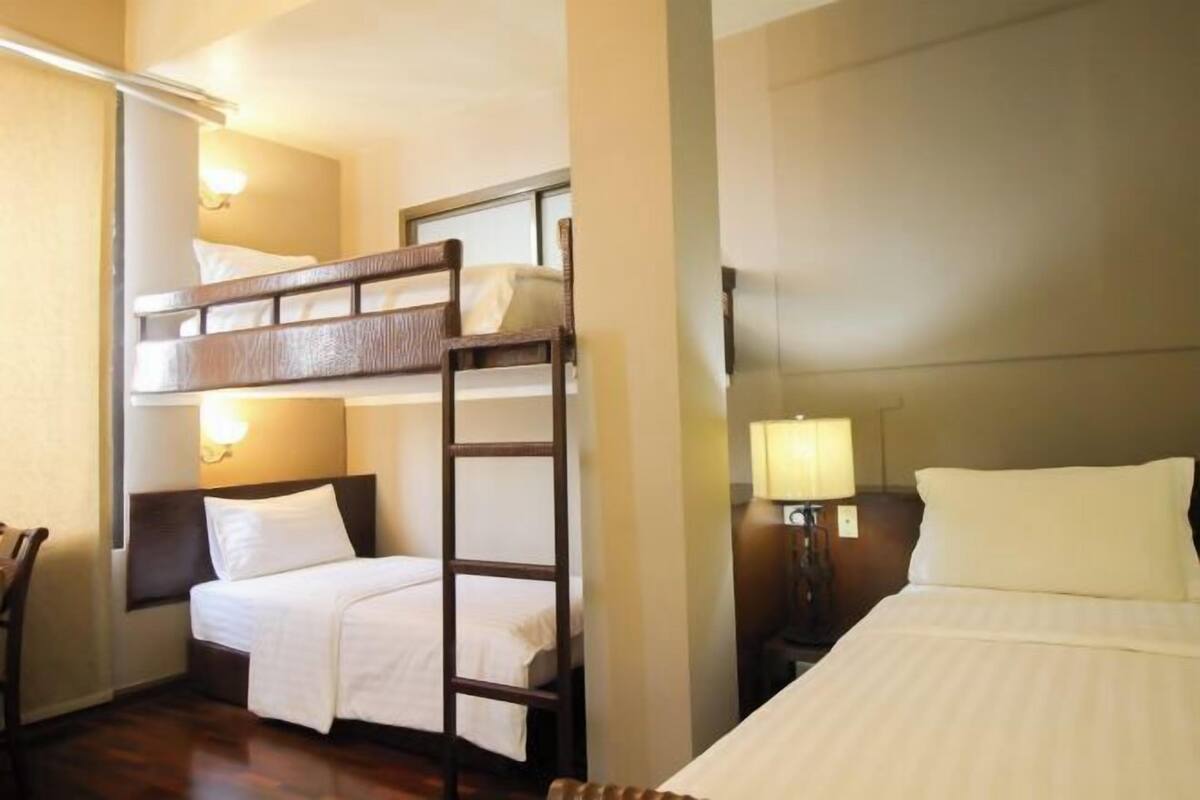 Une chambre d’hôtel avec des lits superposés, une table de chevet avec une lampe et une chaise.
