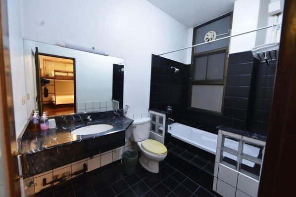 Un baño con piso de baldosas blanco y negro, un inodoro blanco, un lavamanos blanco y una bañera.