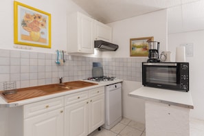 A kitchen with white cabinets, a gas stove, a dishwasher, a microwave, and a coffee maker.