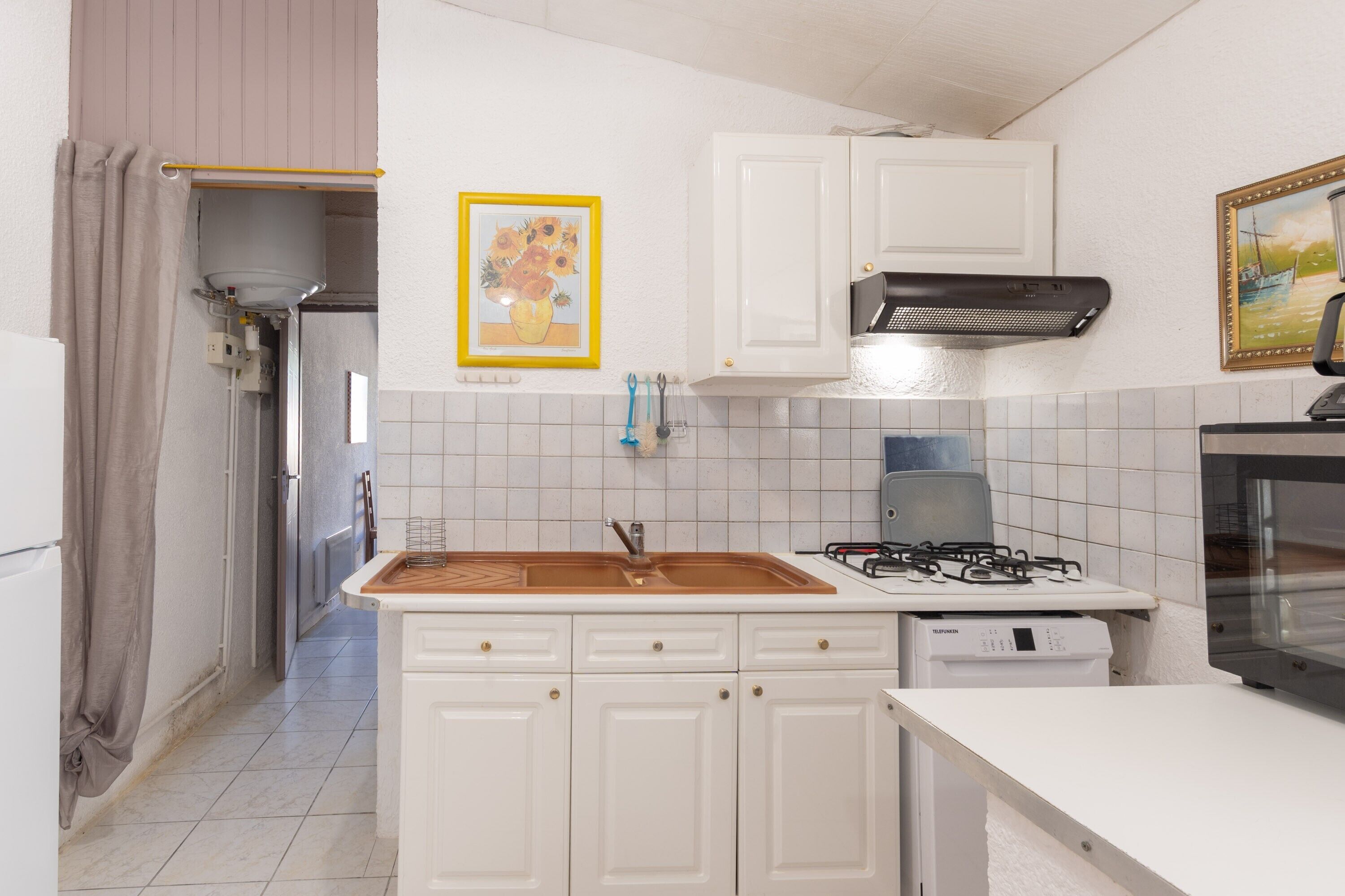 Een keuken met witte kastjes, een gasfornuis, een vaatwasser en een magnetron.