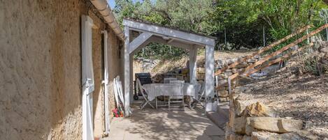 Un espace extérieur aménagé avec une table et des chaises, une pergola et un mur en pierre.