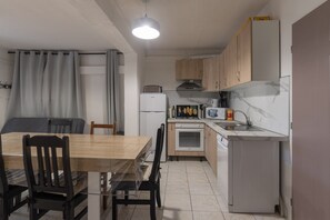 Une cuisine compacte comprenant une table à manger, des chaises, un réfrigérateur, un four à micro-ondes et une cuisinière.