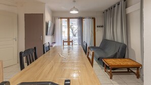 A dining area with a wooden table, chairs, a sofa, and a small wooden table. - Holiday Home 'Gîte 1 - La Tour' with Lake View and Wi-Fi (Saint-Sauveur de Cruzières)