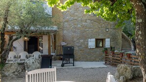 A stone building with a wooden door, outdoor seating, and a barbecue grill. - Holiday Home 'Gîte 1 - La Tour' with Lake View and Wi-Fi (Saint-Sauveur de Cruzières)