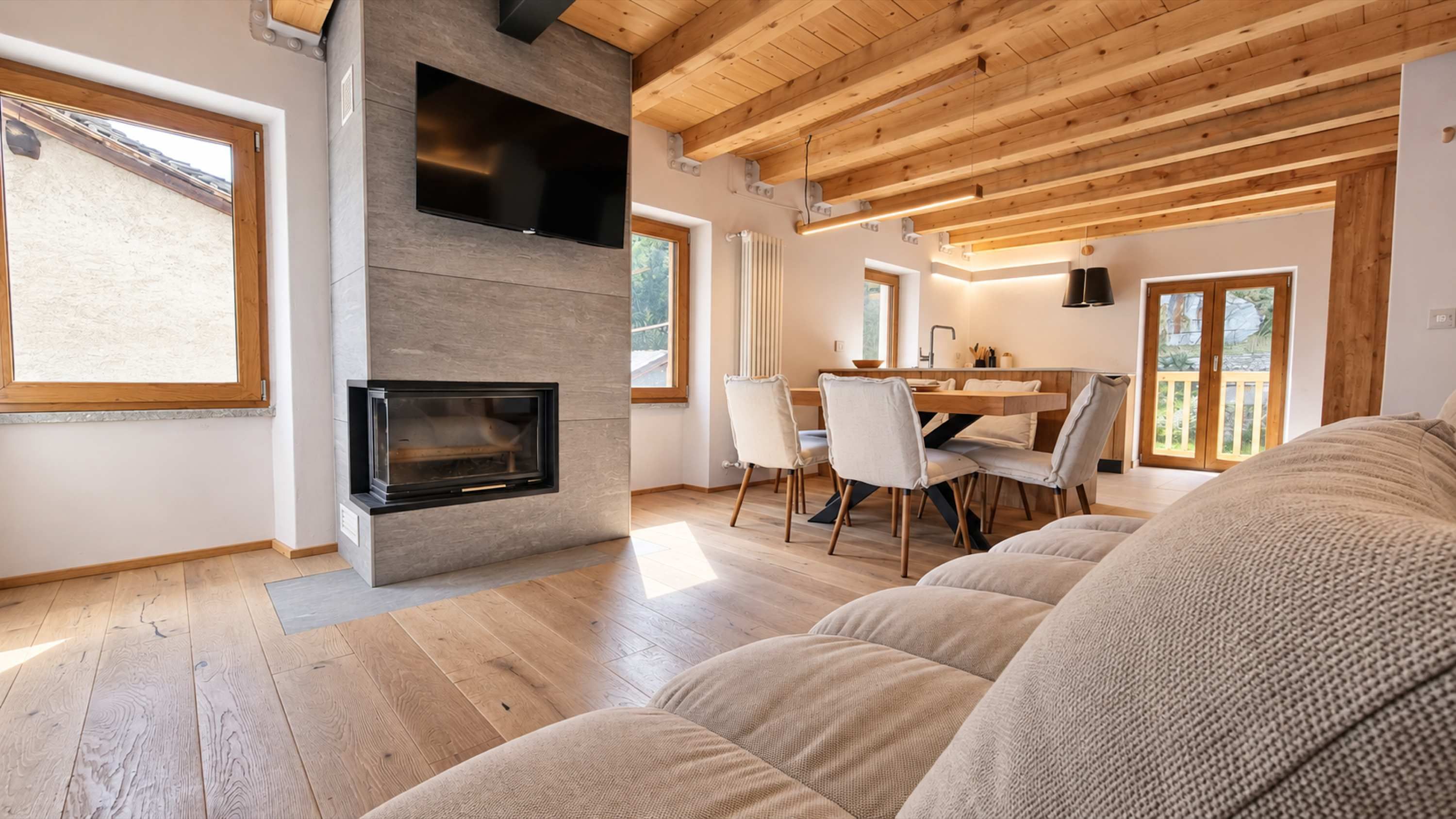 Un soggiorno moderno con camino, pavimento in legno e zona pranzo con sedie e tavolo.