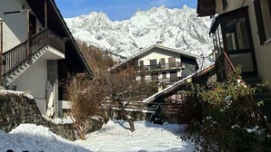 A snow-covered village with traditional buildings, a wooden fence, and a mountain backdrop. - Alpine Chic Retreat (Courmayeur)