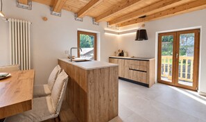 Une cuisine moderne avec des meubles en bois, un îlot central et une vue sur l’extérieur grâce à de grandes fenêtres.