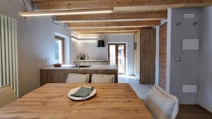 Une cuisine moderne avec des poutres en bois, une table à manger avec un set de table, et une vue sur l’espace repas.