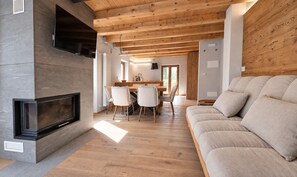 A modern living room with a fireplace, wooden ceiling, and a sofa. - Alpine Chic Retreat (Courmayeur)