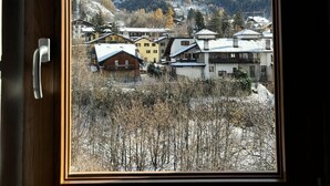 A window view of a mountain village with snow-covered houses and mountains in the background. - Alpine Chic Retreat (Courmayeur)