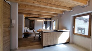 Une cuisine moderne avec des poutres en bois, un coin repas comprenant un canapé et une table, et une vue par la fenêtre.