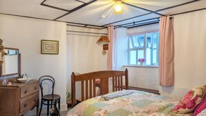 Une chambre à coucher avec un lit en bois, une commode, une chaise et une fenêtre avec des rideaux.