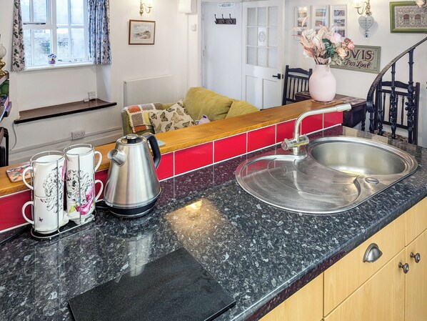 A kitchen with a granite countertop, stainless steel sink, and a coffee maker.