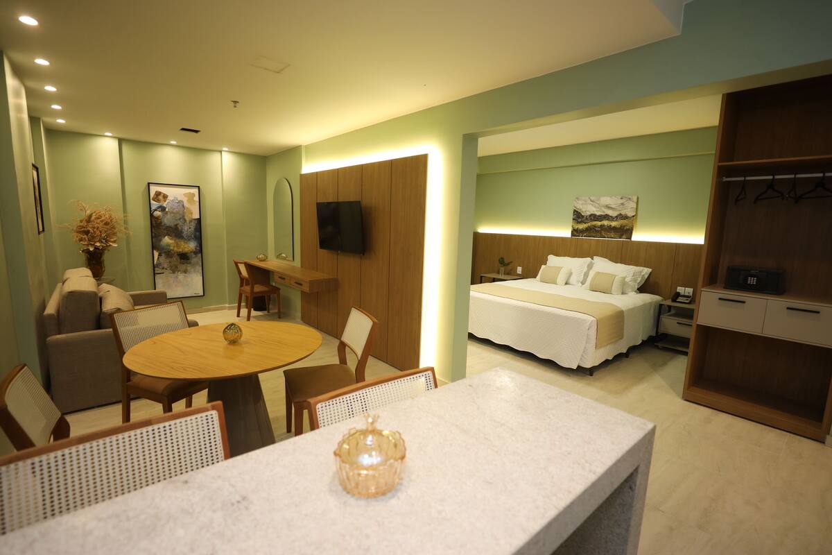 Ein Hotelzimmer mit Bett, Schreibtisch, Esstisch und Sitzecke.