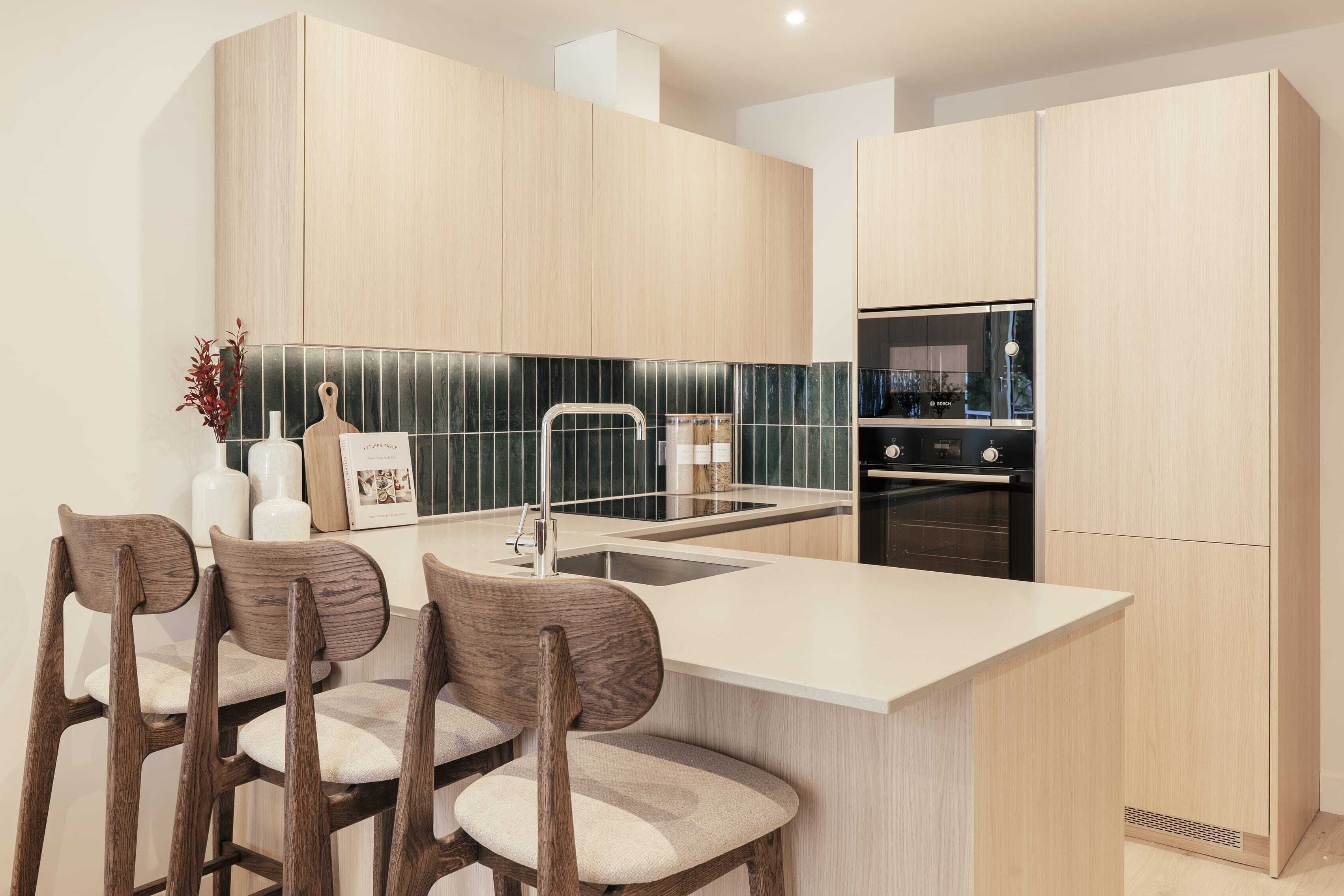 A modern kitchen with a central island, wooden cabinets, a black tiled backsplash, and a built-in oven.