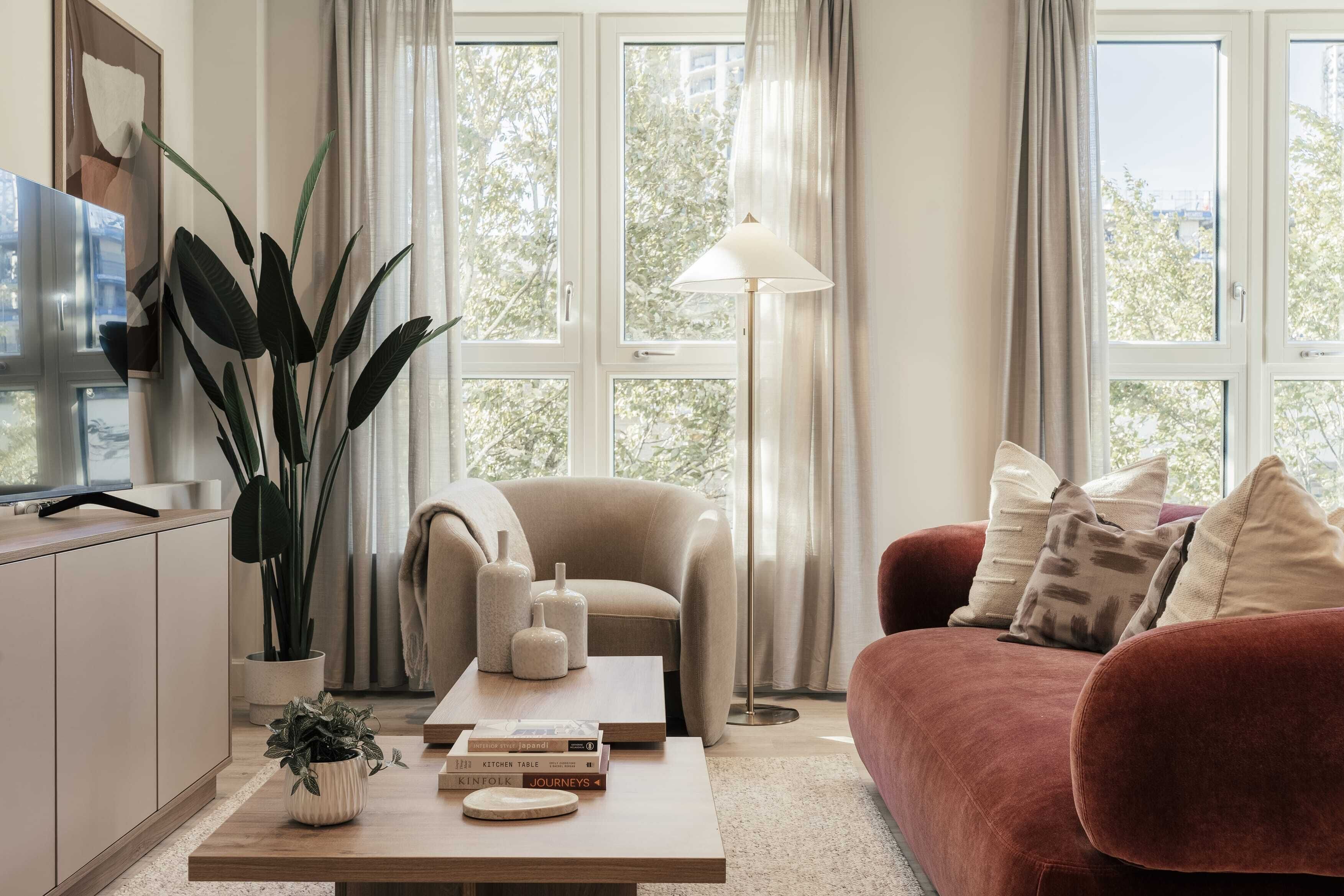 A modern living room with a sofa, a coffee table, a chair, and a large window with curtains.
