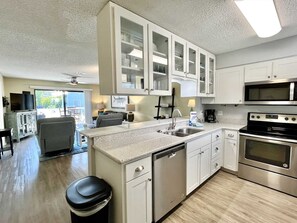 Une cuisine moderne avec des meubles blancs, un lave-vaisselle, une cuisinière et un four à micro-ondes.