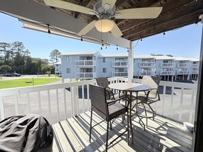 A balcony with a table and chairs, a ceiling fan, and a view of a row of white buildings. - Bayview 23 2 Bedroom Condo (Orange Beach)