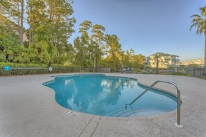 An outdoor swimming pool with a metal ladder, surrounded by trees and a fence. - Bayview 23 2 Bedroom Condo (Orange Beach)