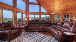 A spacious living room with a large sectional sofa, a plaid rug, and large windows offering a mountain view. - God's View - Pet Friendly, Blue Ridge GA (Blue Ridge)