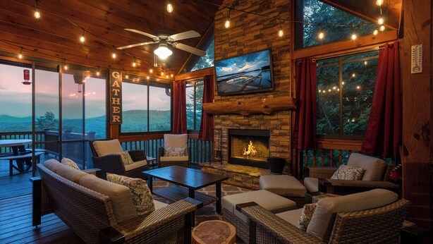 A cozy outdoor seating area with wicker furniture, a fireplace, and a TV mounted on the wall. - God's View - Pet Friendly, Blue Ridge GA (Blue Ridge)