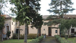 A traditional building with a tiled roof, surrounded by well-maintained gardens and trees.