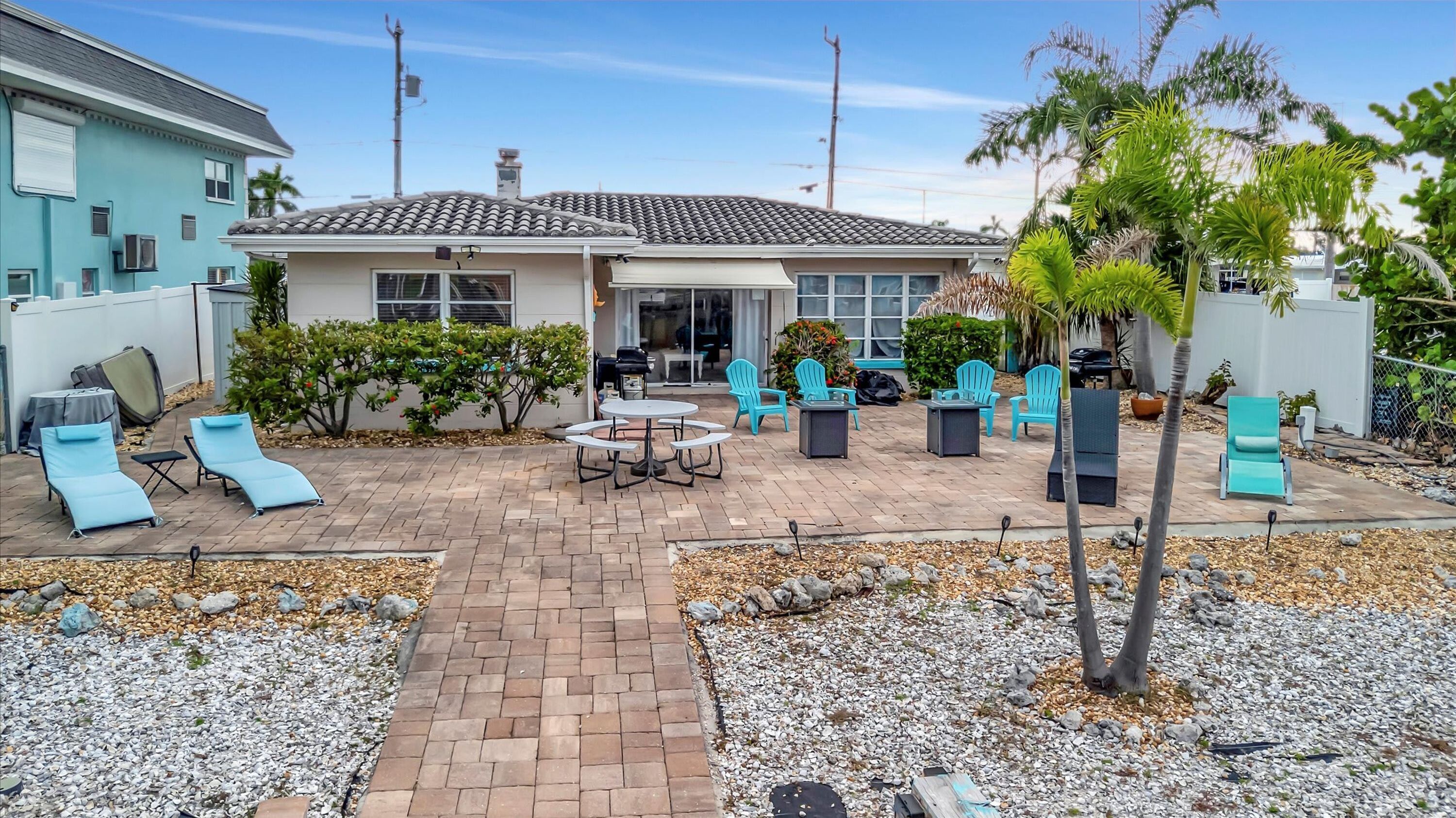 A patio area with lounge chairs, a table, and a grill.