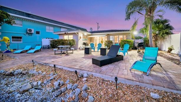 A patio area with lounge chairs, a table, and a grill. - Seashell Suite 1B Pet Friendly Waterfront Dock (Treasure Island)