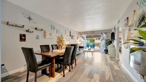A dining area with a wooden table and chairs, a wall with various decorations, and a view into another room. - Dolphin Suite 2B Pet Friendly Waterfront Dock (Treasure Island)