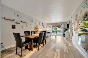 A dining area with a wooden table and chairs, a wall with various decorations, and a view into another room. - Dolphin Suite 2B Pet Friendly Waterfront Dock (Treasure Island)