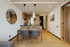 A modern kitchen with wooden cabinets, a dining table with chairs, pendant lights, and a large mirror on the wall. - w Fabulous 1BR With Elegant Balcony in Roma Nte (Mexico City)