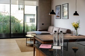 A modern hotel room with a large window, a sofa, a coffee table, and a reception desk with a welcome sign. - w Fabulous 1BR With Elegant Balcony in Roma Nte (Mexico City)
