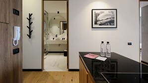 A modern hotel room with a wooden door, a coat rack, a black countertop with a mirror, a framed picture, and a bathroom visible through an open door. - w Fabulous 1BR With Elegant Balcony in Roma Nte (Mexico City)
