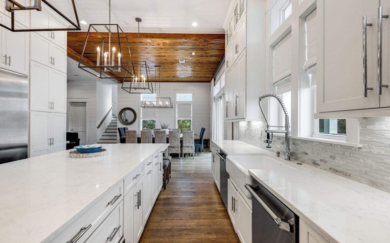 A modern kitchen with white cabinetry, a central island, and a wooden ceiling.