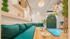 A modern interior with a teal sofa, a small pool, and decorative lighting. - Riad Imrani - swimming pool - 6 mn from Jamaa Al Fna (Marrakech)