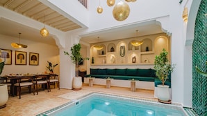 A pool area with a seating area, a dining setup, and decorative lighting. - Riad Imrani - swimming pool - 6 mn from Jamaa Al Fna (Marrakech)