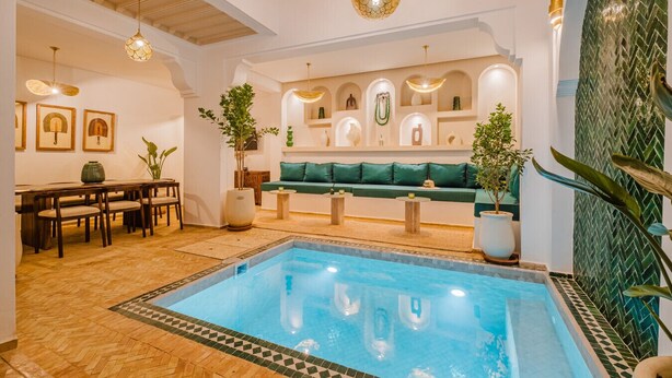 A spacious indoor pool area with a seating area, wooden flooring, and decorative lighting. - Riad Imrani - swimming pool - 6 mn from Jamaa Al Fna (Marrakech)