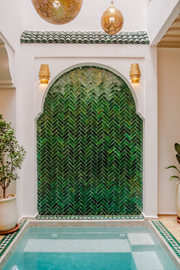 A pool area with a green mosaic wall and a tiled floor. - Riad Imrani - swimming pool - 6 mn from Jamaa Al Fna (Marrakech)
