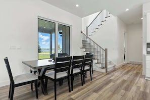 Un comedor con mesa y sillas, una escalera y vistas al exterior.