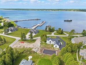 An aerial view of a lakeside property with houses, a dock, and boats. - New Build Baileys Harbor-sunset view & pool table (Baileys Harbor)