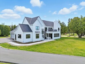 A two-story house with a front porch, a garage, and a landscaped yard. - New Build Baileys Harbor-sunset view & pool table (Baileys Harbor)