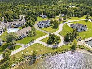 Vista aérea de una zona residencial con casas, una piscina y un río.