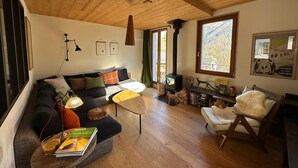 A cozy living room with a wooden ceiling, a sofa, a coffee table, and a fireplace. - Le Nevada - Duplex T4  Proche Centre (Chamonix-Mont-Blanc)
