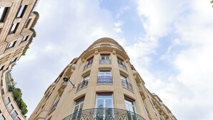 A multi-story building with a curved facade, balconies, and a clear sky. - Appartement de Luxe avec terrasse Champs Elysées (Paris)